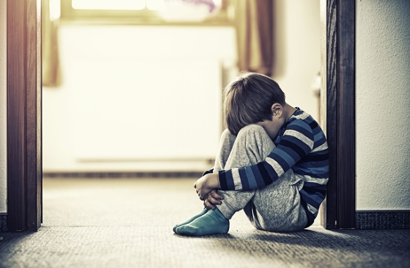 child sitting curled up against door